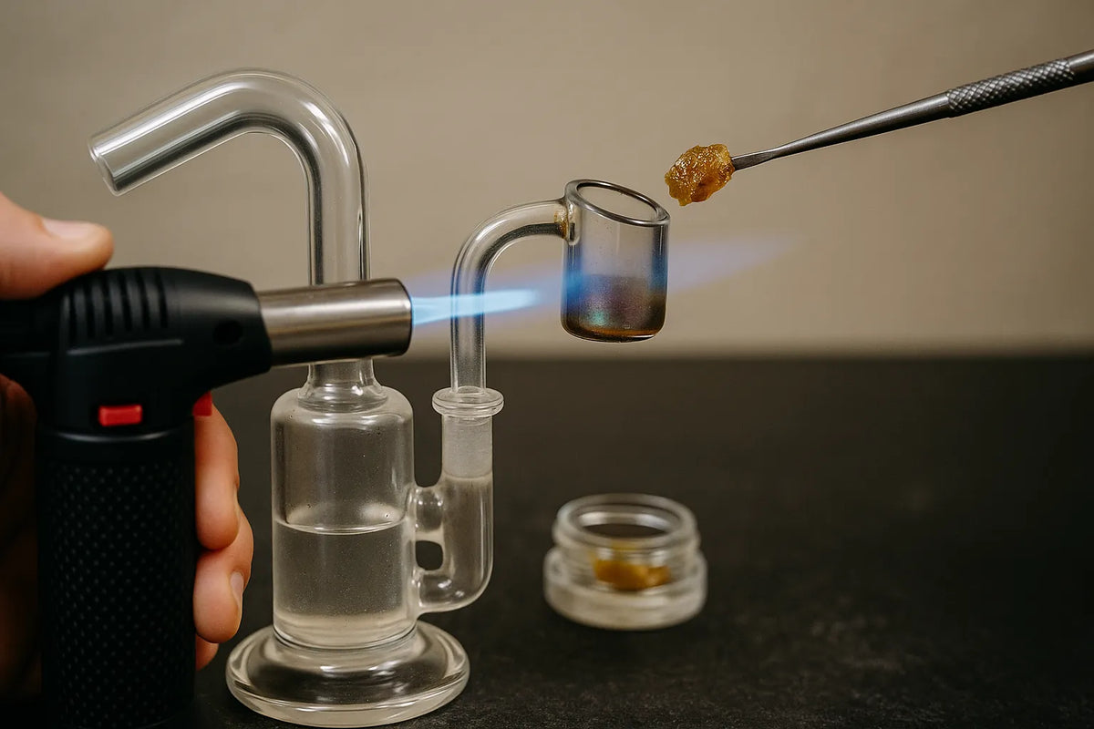 Osoba používa dab rig na vdychovanie kanabisového koncentrátu, detailný záber v uvoľnenom domácom prostredí.